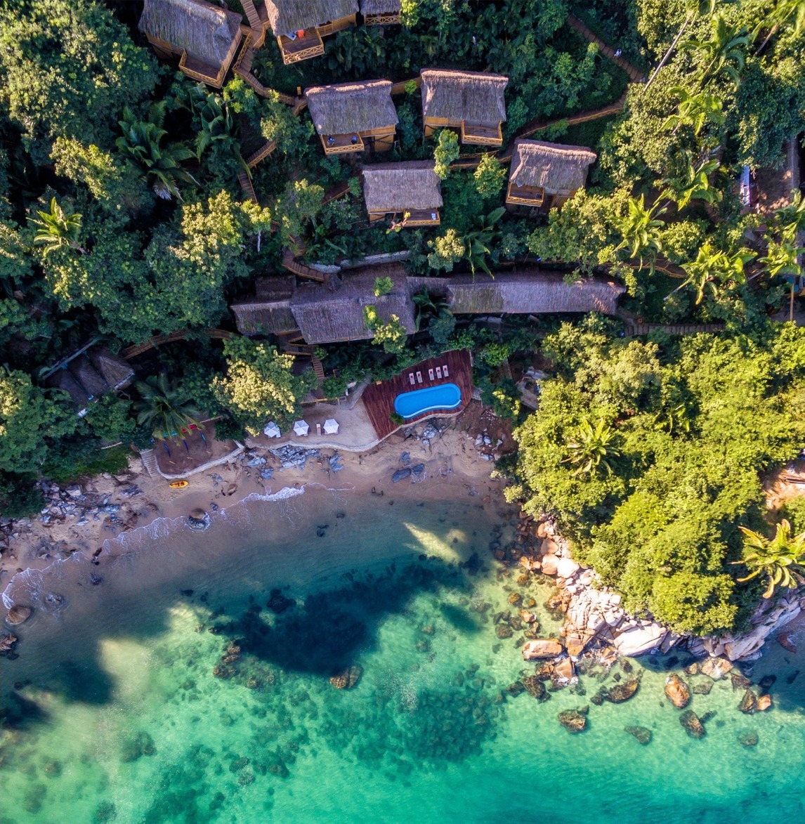 Aerial view of Xinalani’s jungle casitas beside turquoise ocean